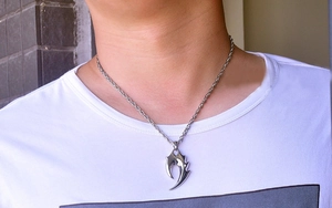 Detailed close-up of a sharp silver claw pendant with a twisted rope chain on a model