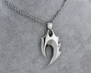 Macro shot of silver flame skull pendant with inlaid stone and vintage chain detail