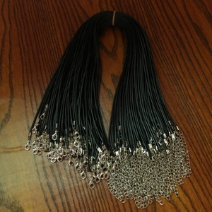 Bulk black waxed cord necklaces with silver lobster clasps on a dark wood background