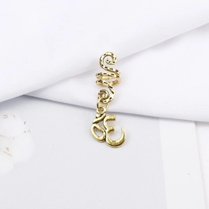 Macro shot of gold Om symbol pendant on spiral hair ring accessory with vintage texture