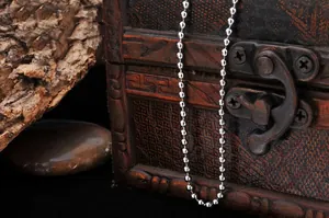 Macro shot of silver ball chain necklace on rustic wood and stone background