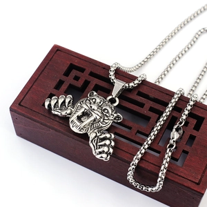 Détail d'un pendentif tigre à dents de sabre argenté sur boîte en bois vintage