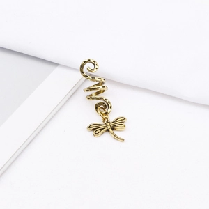 Detail of vintage bronze spiral hair coil with a delicate dragonfly pendant on white fabric