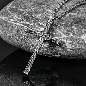 Macro shot of vintage silver cross pendant with bamboo texture on rustic grey rock