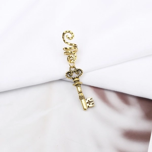 Detail showing a vintage gold alloy spiral hair ring featuring a hollow key pendant
