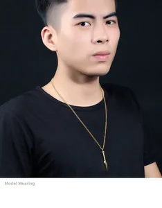Close-up of a gold spearhead pendant necklace on a male model with black t-shirt