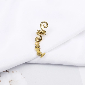 Detail of golden spiral dreadlock clip with a vintage mermaid pendant on white fabric