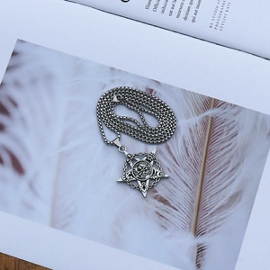 Détail d'un pendentif tête de mort pentagramme argenté avec symboles occultes gothiques