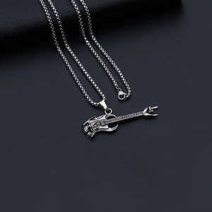 Detail of silver guitar pendant with skull design and rock hand on black leather