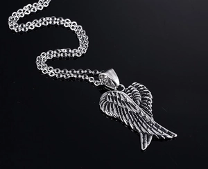 Vintage oxidized silver angel wing pendant necklace on a reflective black surface