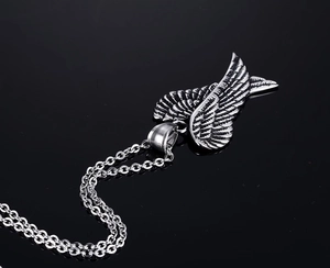 Retro angel wing necklace with blackened steel finish on a dark reflective surface