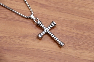 Close-up of a vintage silver cross pendant with spiral texture on a wooden table