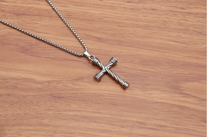 Detailed view of the silver twist rope cross pendant with metal link chain on wood surface