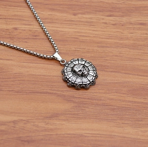 Macro shot of gothic skull pendant with Roman numerals on aged stainless steel