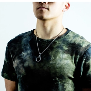 Detail shot of men's chunky silver steel ring pendant with textured edges on a ball chain