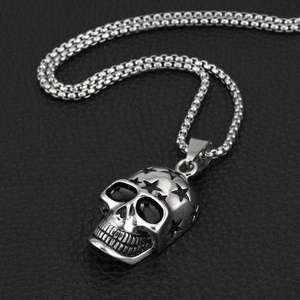 Macro side view of silver punk skull pendant with star detail on black leather backdrop