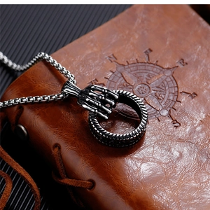 Close-up of vintage punk skull hand holding a ring pendant on a steel box chain