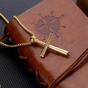 Detail der goldenen Baseballschläger Kreuz-Halskette auf einem Leder-Notizbuch