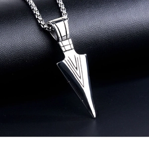 Close-up of polished stainless steel arrowhead pendant with textured box chain on leather