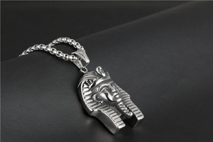 Macro shot of Egyptian Pharaoh pendant and silver box chain on dark leather