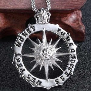 Macro shot of silver compass pendant with starburst design and engraved power success words