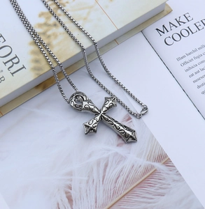 Détail du pendentif croix vintage en acier avec gravures florales et chaîne box robuste