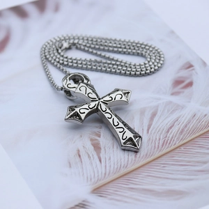 Détail d'un pendentif croix en acier argenté vintage avec textures rétro sur carte
