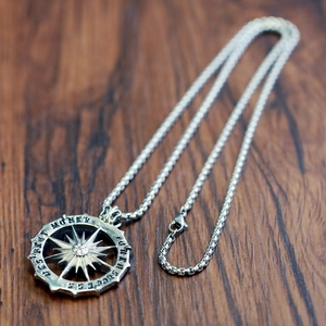 Close-up of vintage sun god pendant in silver finish with engraved text on wooden surface