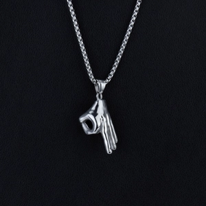 Macro detail of the silver hand gesture pendant and polished box chain on black texture