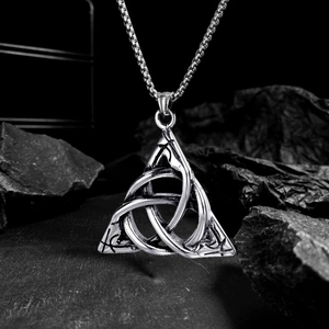 Silver Celtic Triquetra knot pendant necklace for men displayed on black volcanic rock base