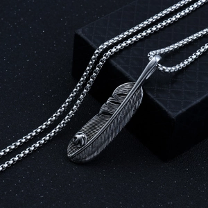 Macro shot of retro silver feather pendant with detailed texture and square chain
