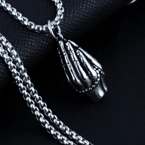 Macro shot of vintage stainless steel praying hands pendant on a round box chain