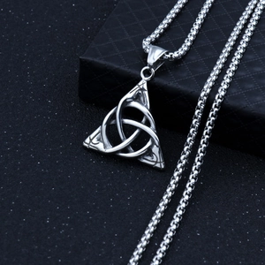 Detailed macro view of silver Celtic Triquetra knot pendant on black textured background