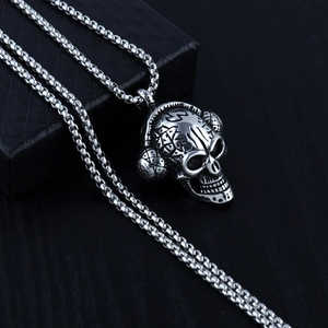 Dettaglio macro del ciondolo teschio punk con cuffie e texture metalliche incise