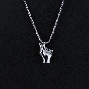Macro shot of polished silver scissor hand gesture pendant with wheat chain on leather
