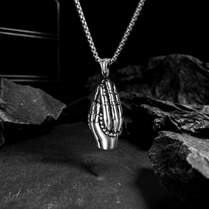 Vintage praying hands pendant in silver steel on a box chain over a dark stone background