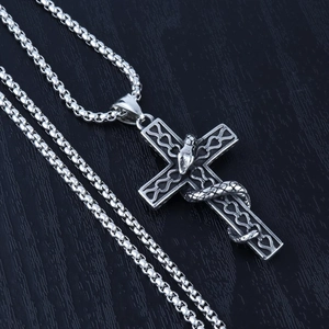 Gothic cross pendant with realistic snake wrap detail on a dark wood background