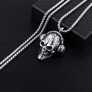 Retro punk skull pendant with headphones and steel box chain on a black wood surface