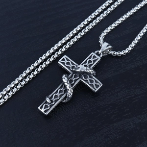 Detail of gothic silver snake pendant with intricate scales on vintage cross necklace