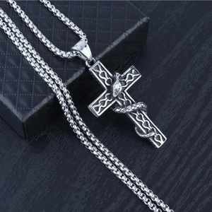 Detailed close-up of gothic silver cross pendant with coiled snake on black leather