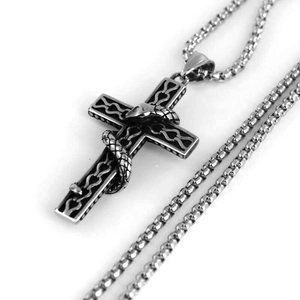 Macro detail of gothic snake wrapped around a vintage steel cross pendant necklace