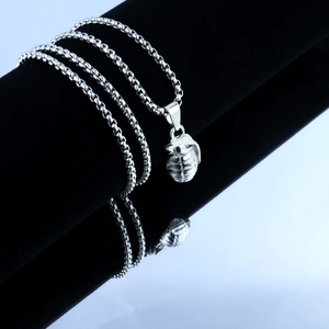 Macro shot of silver grenade pendant with grid texture and round bead chain