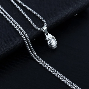 Macro shot of silver stainless steel grenade pendant with box chain on dark leather surface