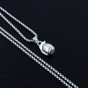 Macro shot of a silver punk grenade pendant with a round box chain on a wooden background