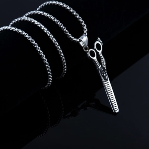 Gros plan du pendentif ciseaux de coiffeur dragon en acier inoxydable avec chaîne maille