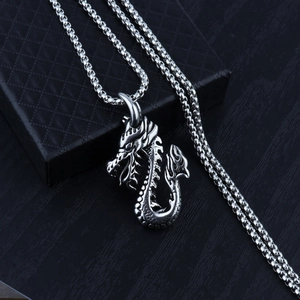 Close-up of vintage steel dragon pendant with intricate scales on a box chain