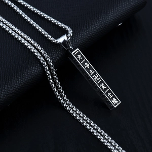 Détail macro du pendentif en acier inoxydable argenté avec caractères bouddhistes gravés