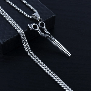 Détail du pendentif ciseaux et peigne de coiffeur sur une boîte noire élégante