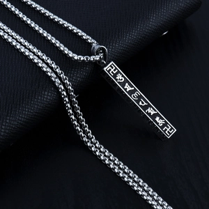 Détail du pendentif pilier argenté avec mantra bouddhiste gravé et chaîne à perles