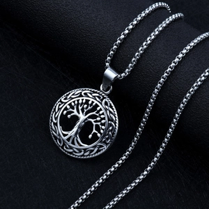 Close-up of silver tree of life pendant with Celtic knot border on black texture
